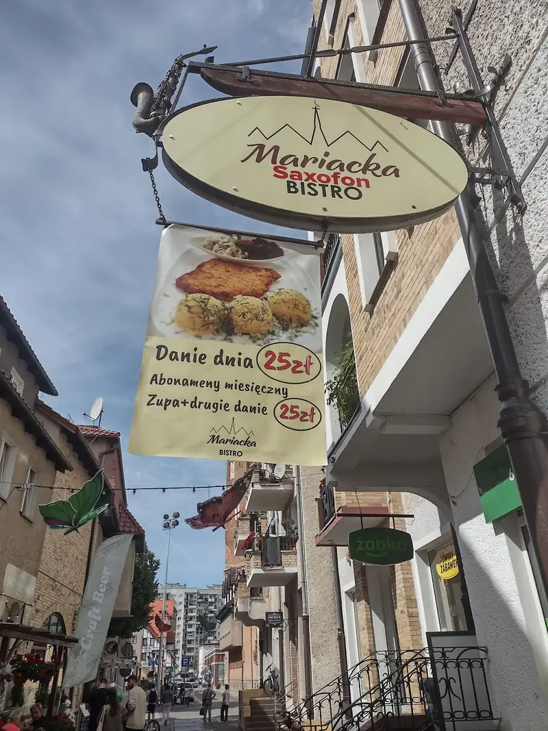 Owalny szyld Mariacka Bistro na wysięgniku nad ulicą Mariacką